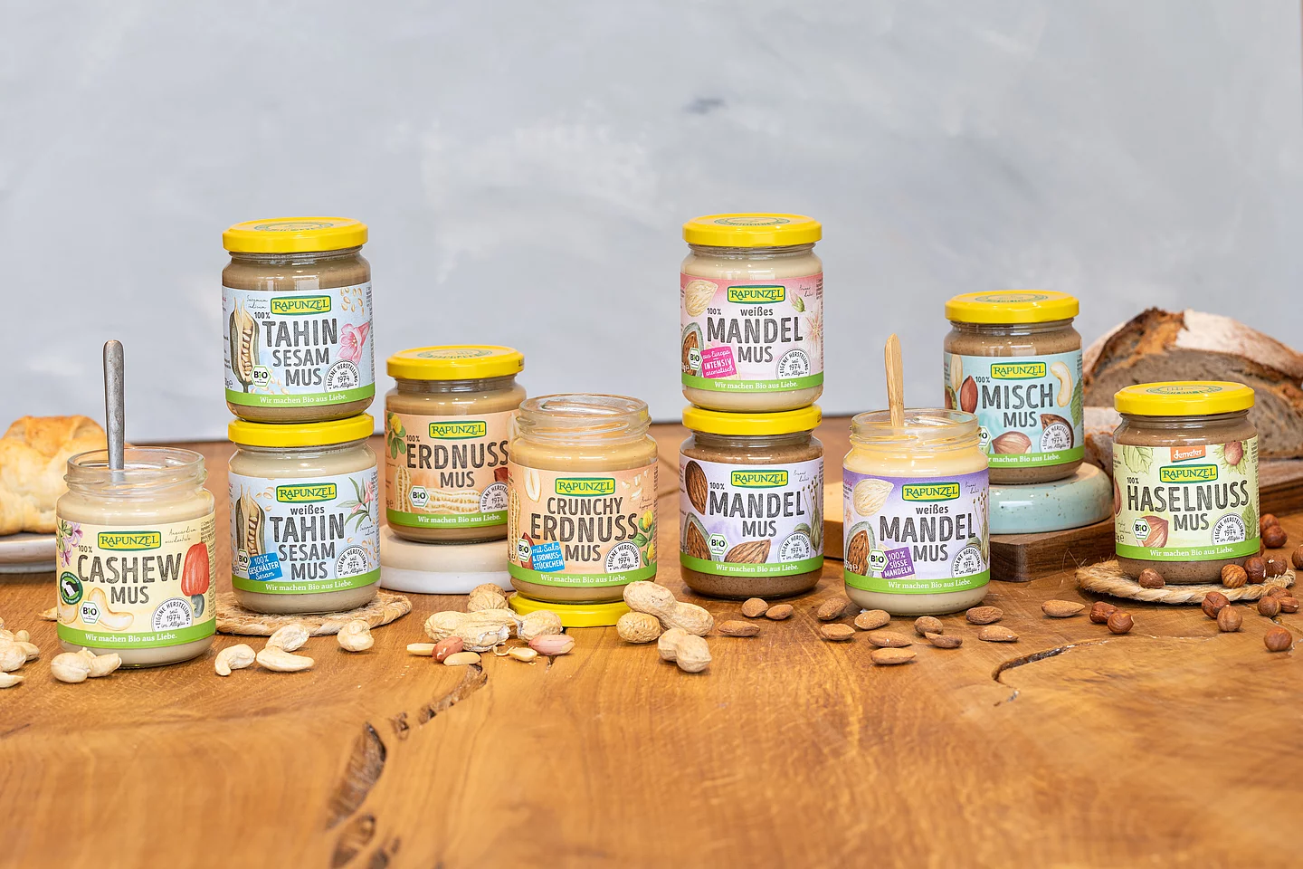 Rapunzel Nussmuse – 100 % Nuss, Bio-Qualität und Vielfalt für deine Rezepte. Rapunzel Nussmuse in Bio-Qualität auf einem Holztisch, im Hintergrund ein Laib Brot – cremige Muse aus 100 % Nuss, ideal für Brotaufstrich und kreative Küche.