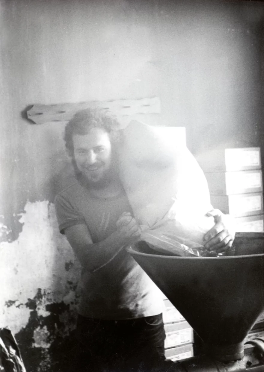Rapunzel stellt seit Anfang der 70er Jahre Nussmuse her. Historisches Schwarz-Weiß-Foto, das einen Mann (Joseph Wilhelm) zeigt, der einen Sack auf der Schulter trägt.