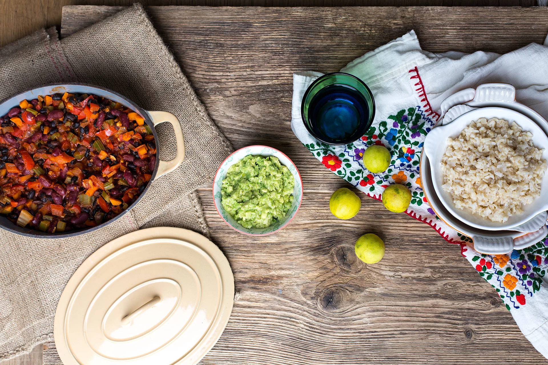 Parboiled Reis überzeugt durch kurze Kochzeit und Vitamine und Mineralstoffe. Chili sin carne in einem Topf neben einer Schüssel Parboiled Spitzenreis Langkorn Natur.