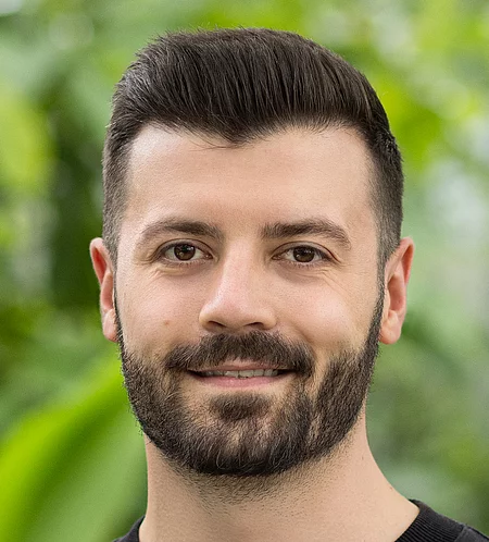 Mario Mößlang Rapunzel Mitarbeiter steht vor blühender Pflanze.